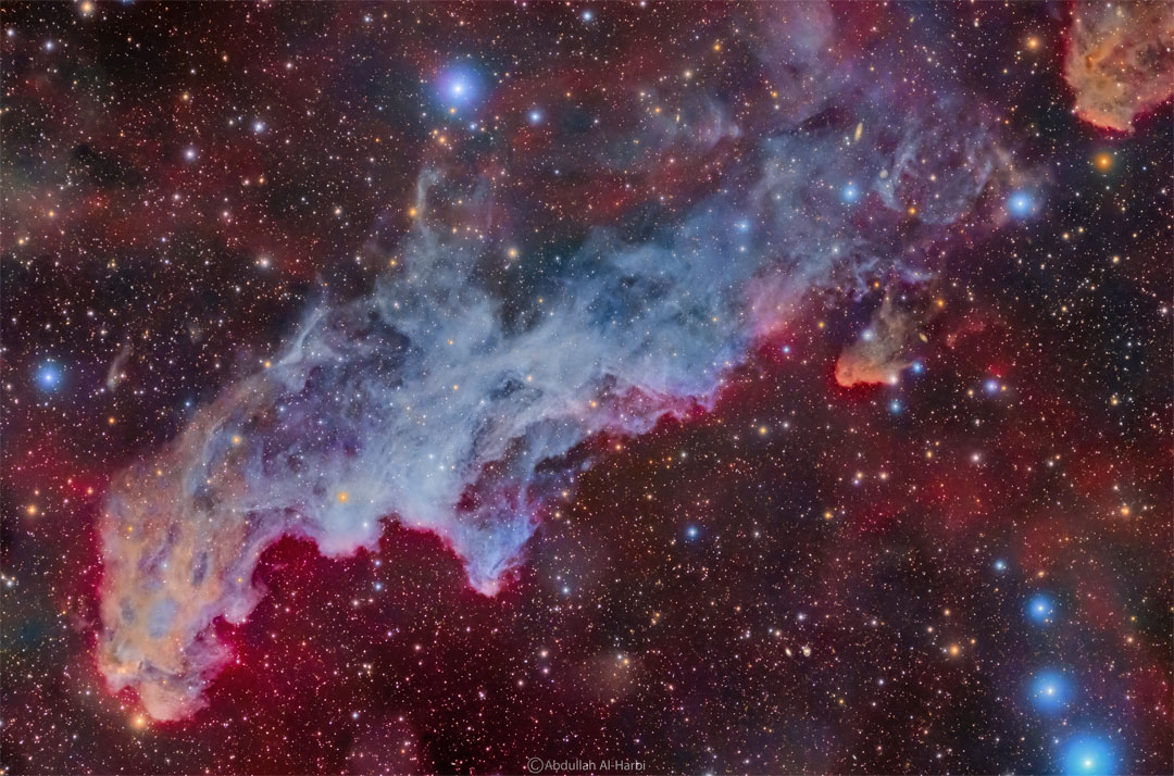 A colorful star field surrounds a big blue reflection nebula.
The nebula is elongated across the wide frame and said to 
resemble the head of folklore-based witch.
Please see the explanation for more detailed information.