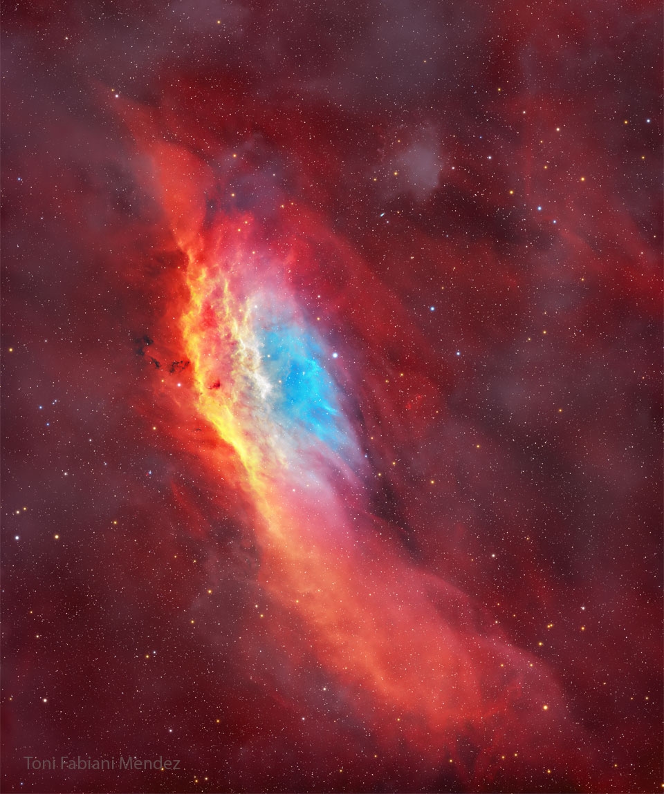 The starry image filled with a red glow features 
a red, yellow, and blue colored nebula. The nebula 
has, roughly, the shape of the US state of California.
Please see the explanation for more detailed information.